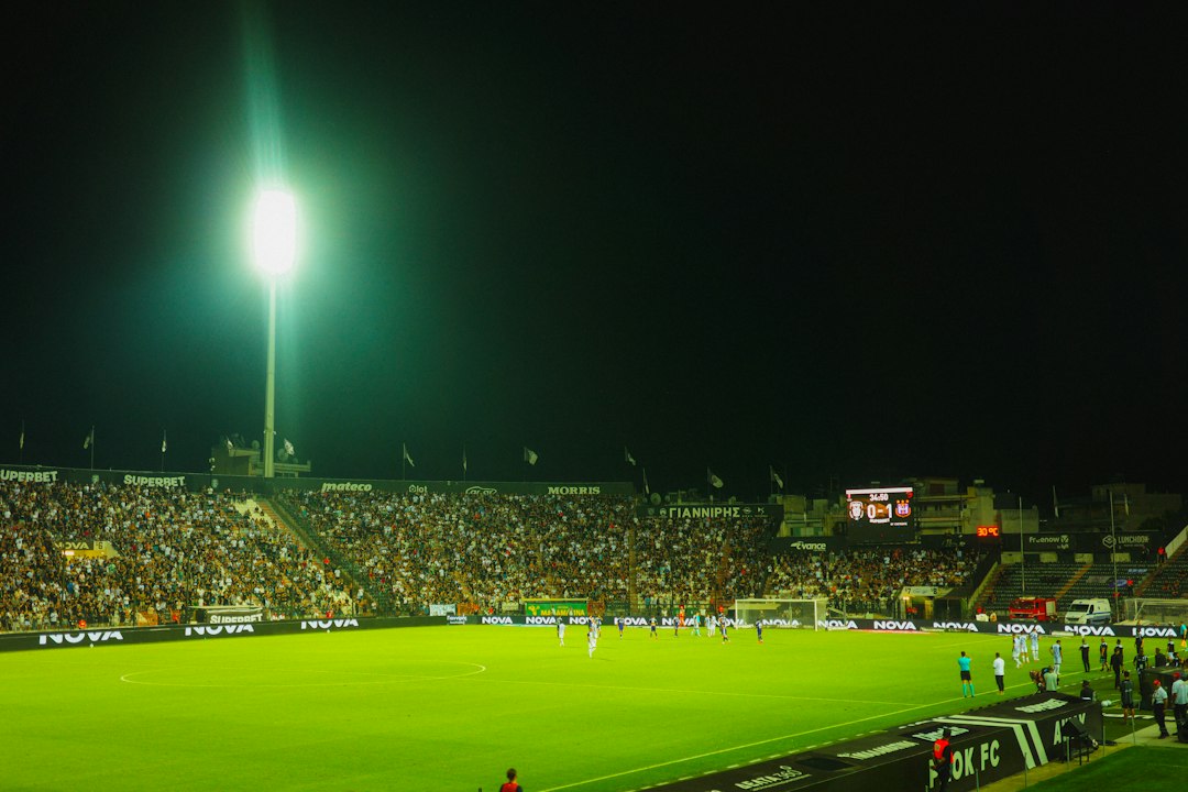 Gece ışıkları altında futbol maçı ve tribünler