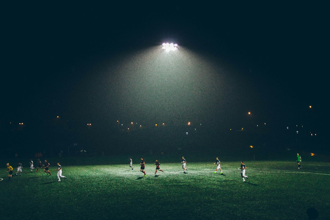 Gece ışıkları altında futbol karşılaşması ve tribünler